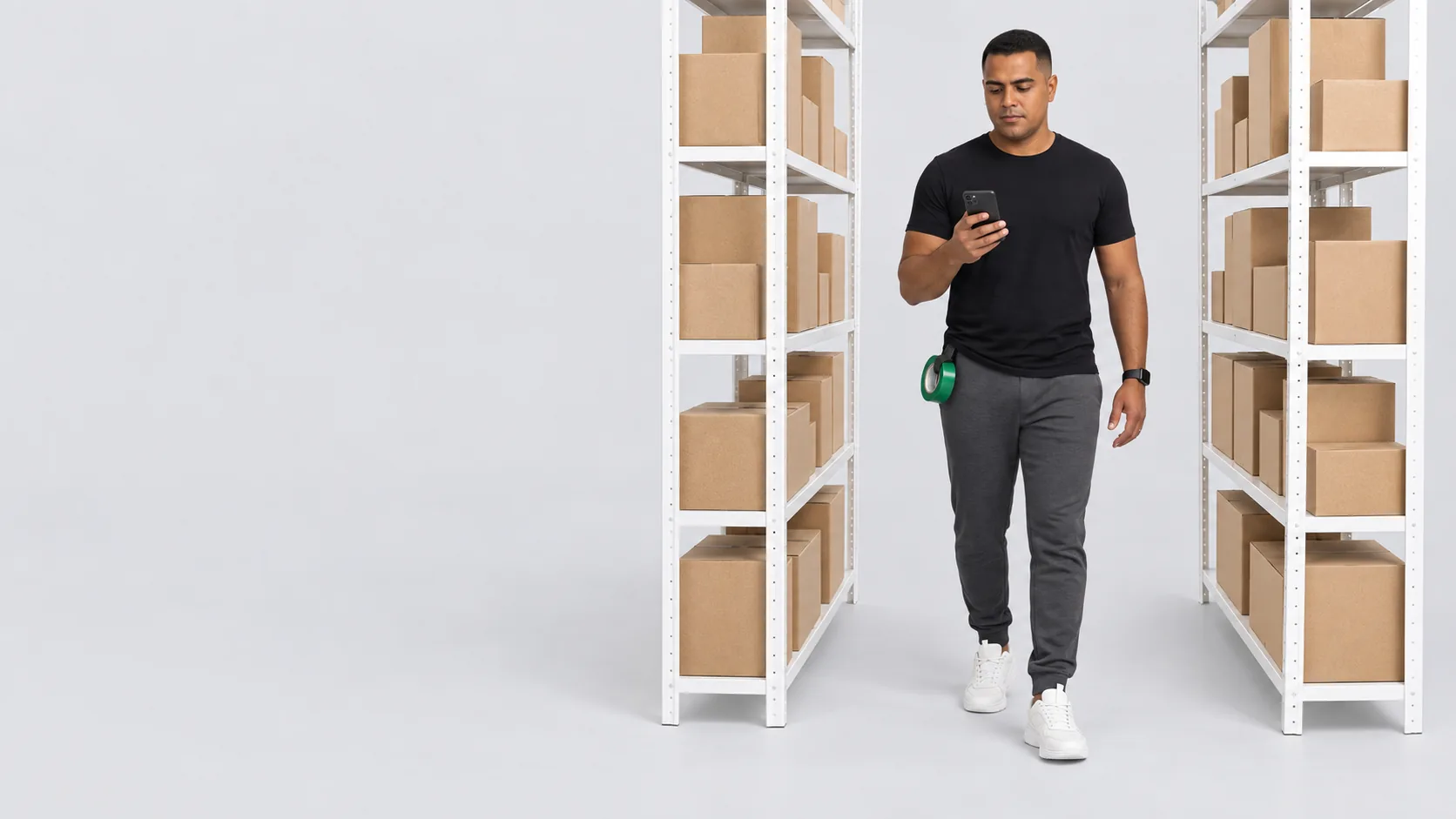 Dono de e-commerce entre estantes de caixas kraft conferindo o celular